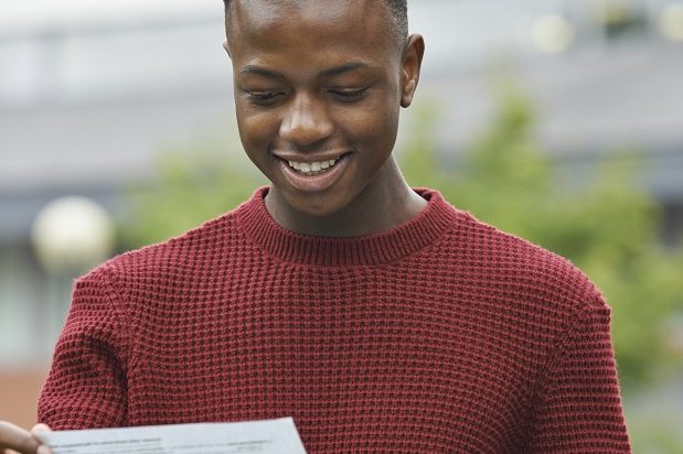 Student looking happy with a piece of paper showing his results